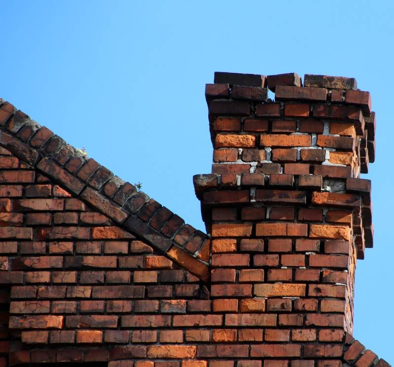 Damaged chimney on an Justin home showing cracks and missing mortar